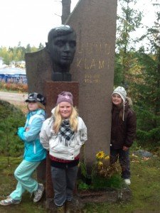 Iloiset tytöt ja Uuno Klamin patsas kirkon pihalla.